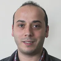 Portrait of Hakkı with light stubble and a plaid shirt.