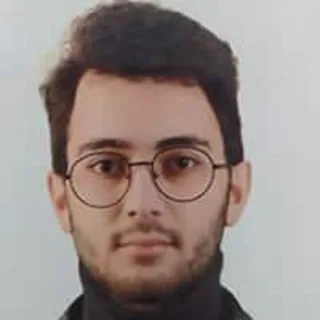 Portrait of Alp Çayıroğlu wearing glasses and a dark top.