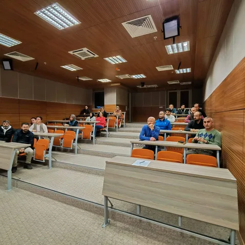 Yapay zekâ okuryazarlığı seminerinde salonun arka bölümünden katılımcı görünümü.