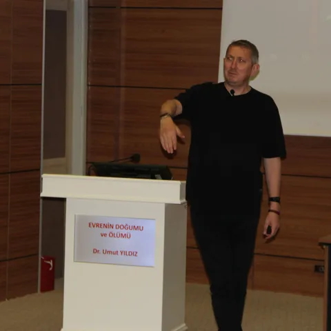 Dr. Umut Yıldız konferans salonunda evrenin doğumu ve ölümü üzerine sunum yapıyor.