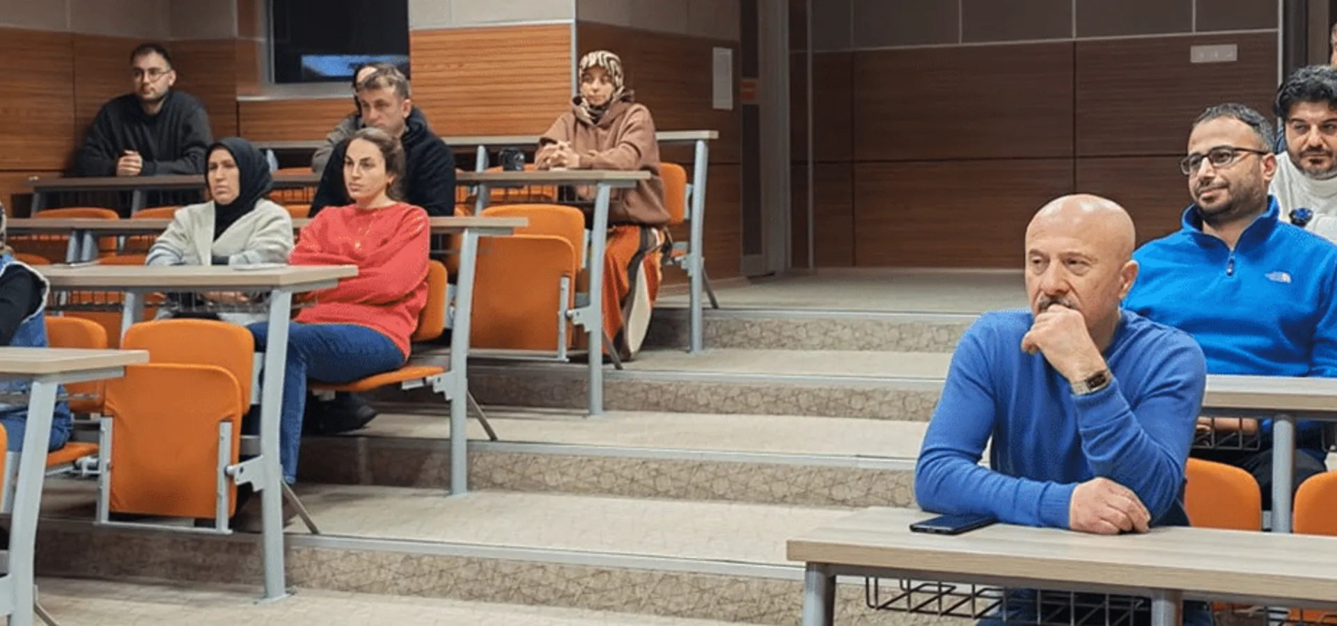 Amfi sıralarında oturan seminer katılımcıları.