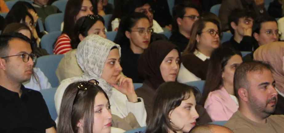 Konferans salonunda sıraları doldurmuş dinleyici topluluğu.