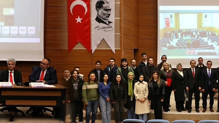 Panel sonunda salonda çekilmiş toplu fotoğraf; arkada Türk bayrağı, Atatürk portresi ve UZEM tabelası.