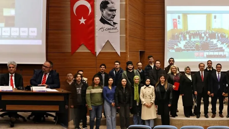 Panel sonunda salonda çekilmiş toplu fotoğraf; arkada Türk bayrağı, Atatürk portresi ve UZEM tabelası.