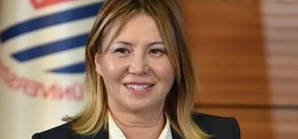 Ondokuz Mayıs Üniversitesi flaması önünde gülümseyen bir akademisyen.