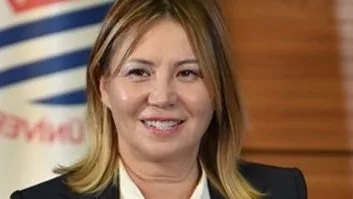 Ondokuz Mayıs Üniversitesi flaması önünde gülümseyen bir akademisyen.