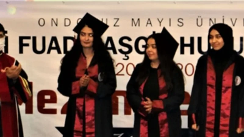 Mezuniyet töreninde sahnede duran cübbeli mezunlar; arkalarında "Ondokuz Mayıs Üniversitesi Ali Fuad Başgil Hukuk Fakültesi Mezuniyet Töreni" pankartı var.