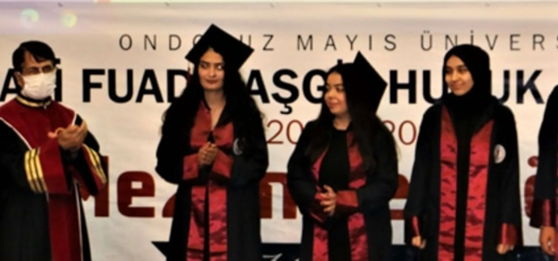 Mezuniyet töreninde sahnede duran cübbeli mezunlar; arkalarında "Ondokuz Mayıs Üniversitesi Ali Fuad Başgil Hukuk Fakültesi Mezuniyet Töreni" pankartı var.